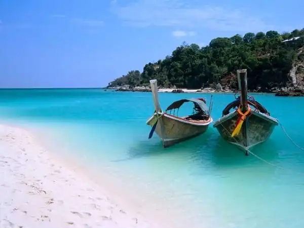 Two boats perched on a white sand shore of Zanzibar.